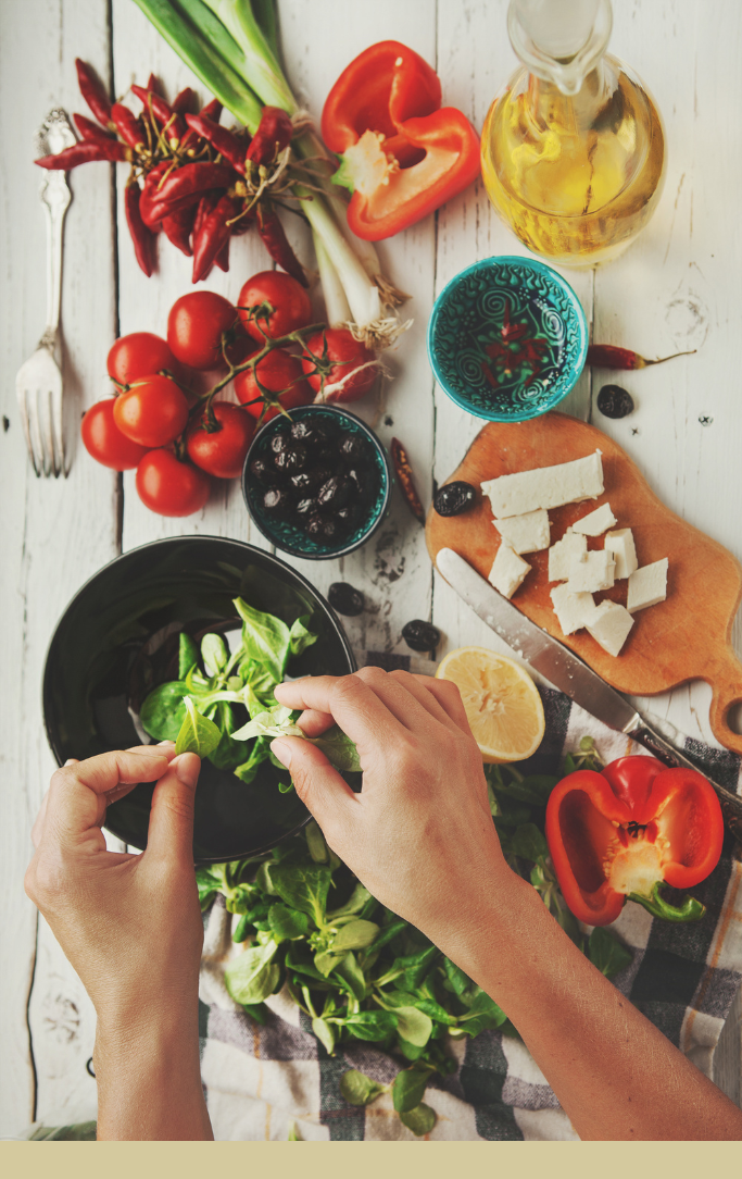 hands putting together a dish with a variety of vegetables on a table.